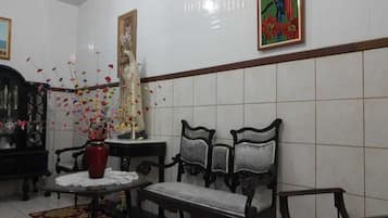 Um quarto com parede de azulejos, um vaso vermelho com flores, um armário de madeira e um quadro.