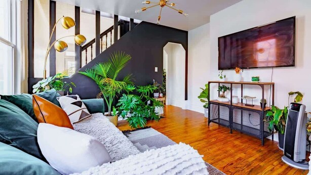 A modern living room with a staircase, wooden flooring, and a large flat-screen TV. - Short North/Downtown | Near High St | Walk to Convention Center | 5,800+ Reviews (Columbus)