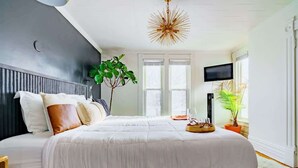 A bedroom with a large bed, a TV, and a plant. - Short North/Downtown | Near High St | Walk to Convention Center | 5,800+ Reviews (Columbus)