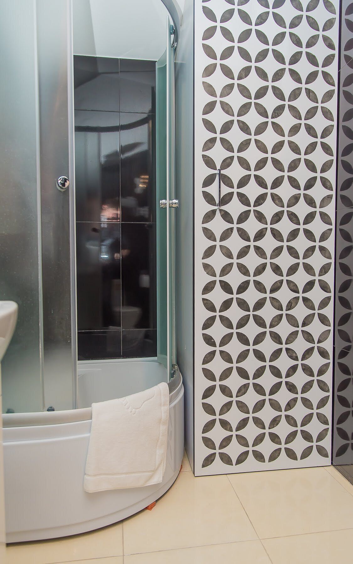 Un baño con ducha envuelta en vidrio, inodoro blanco y pared con diseño.