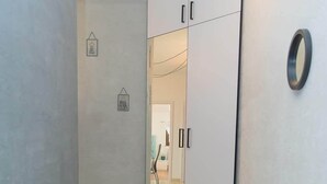 A corridor with a sliding door leading to a room. The walls are plain, and there are two circular wall decorations. The floor is tiled.