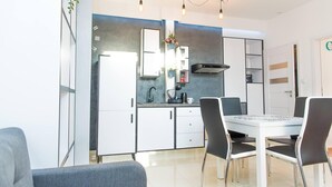 A modern kitchen with white cabinets, a black stove, and a dining area with a white table and four chairs.