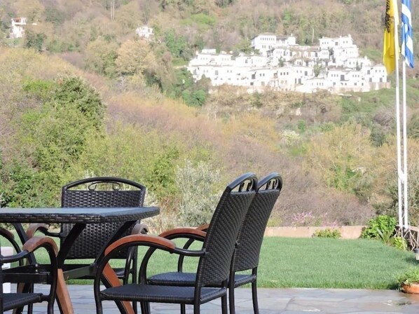A patio with wicker furniture and a view of a hillside with white buildings. - Villa Mylopotamos (Zagora-Mouresi)