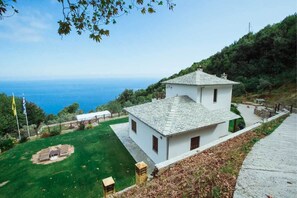 Un edifici blanc amb teulada a bandes, ubicat en un turó amb vista al mar.