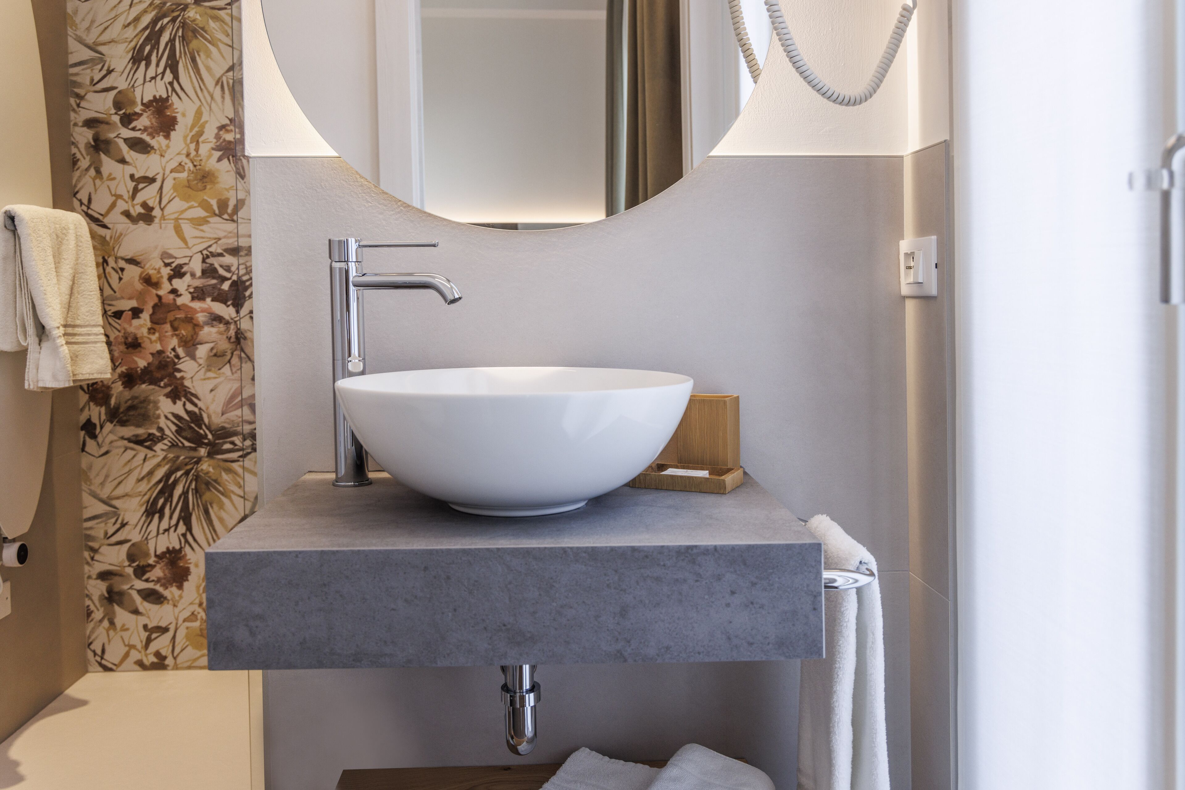 A modern bathroom with a large white sink, a mirror, and a towel rack.
