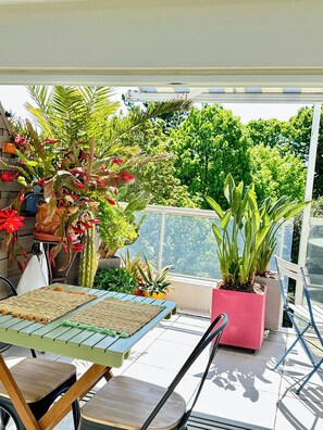 Un espace patio aménagé avec une table, des chaises et diverses plantes en pot.