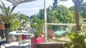 A covered outdoor area with a table, chairs, and potted plants. - Appt COCOONING, Nice Terrace + BIKES 🤩PROXIMITY OF 2 BEAUTIFUL BEACHES 🏖️et PORT (La Baule)