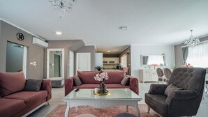 A modern living room with a sofa, armchair, ottoman, and a glass coffee table with a vase of flowers. - Luxury villa Tori in Imotski, pool (Lokvicici)