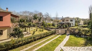 A residential area with a paved pathway, a small garden, and a white house with a sloped roof. - Villa Helios (South Pelion)