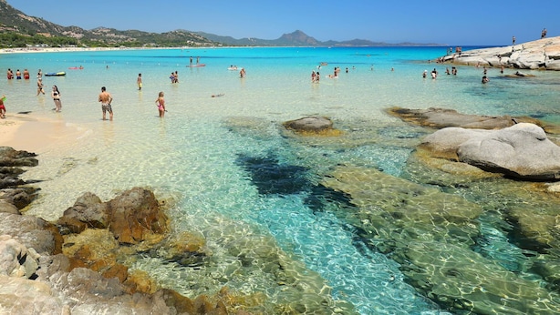 A beach with clear turquoise water, rocky formations, and people swimming and sunbathing. - Cosy apartment in villa for 6 people with A/C, TV, terrace and pets allowed (Castiadas)