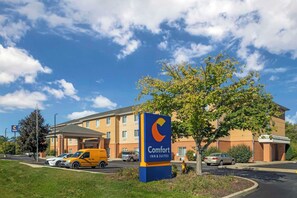 A Comfort Inn & Suites hotel with a clear blue sky and a parking lot.
