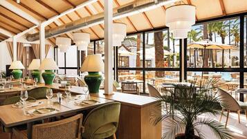 Un restaurante con terraza, amplios ventanales y techo de madera.