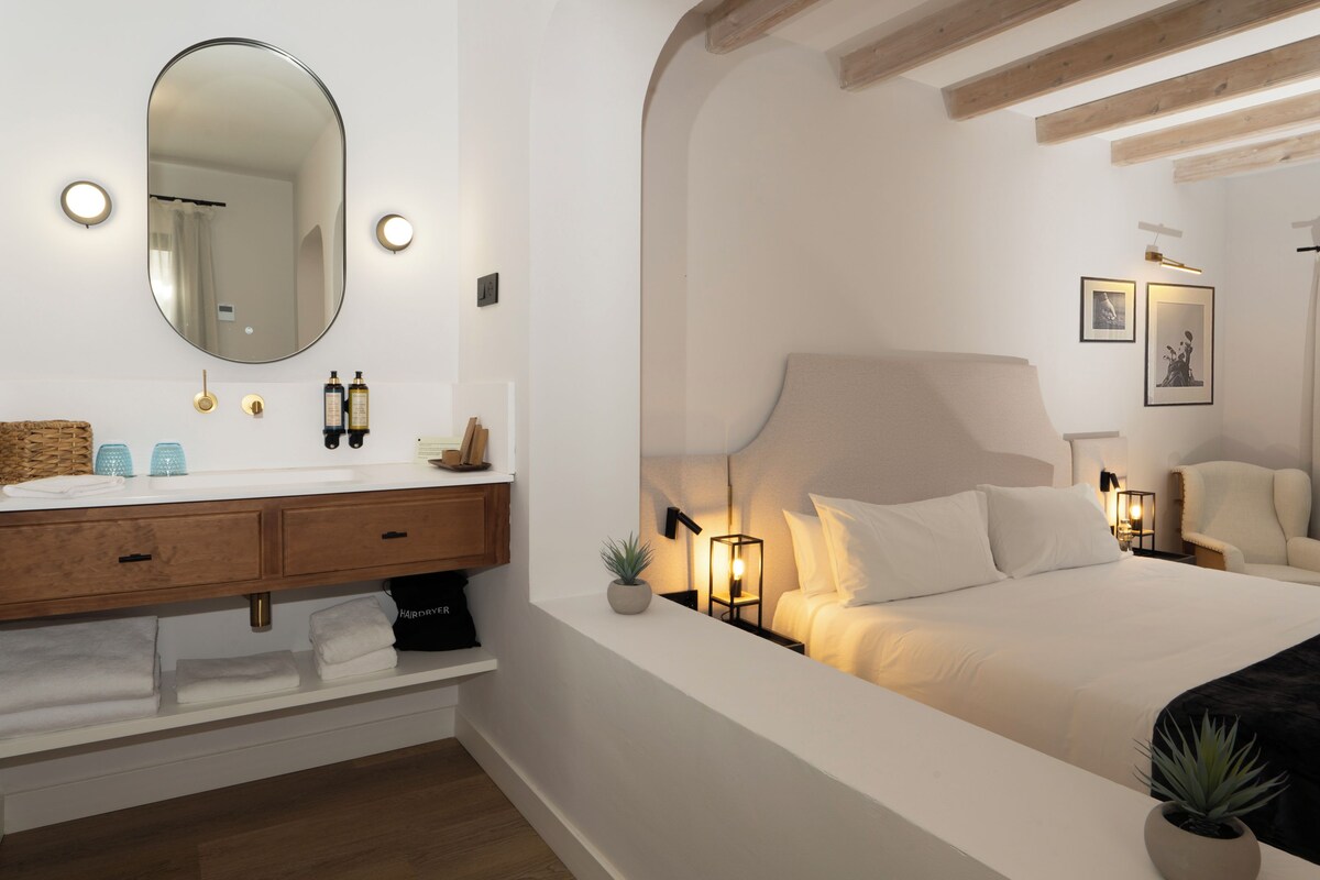 Une chambre à coucher moderne avec un grand lit, des lampes de chevet, un miroir et une petite plante.