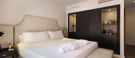Una habitación de hotel con una cama grande, mesita de noche y un armario con espejo.