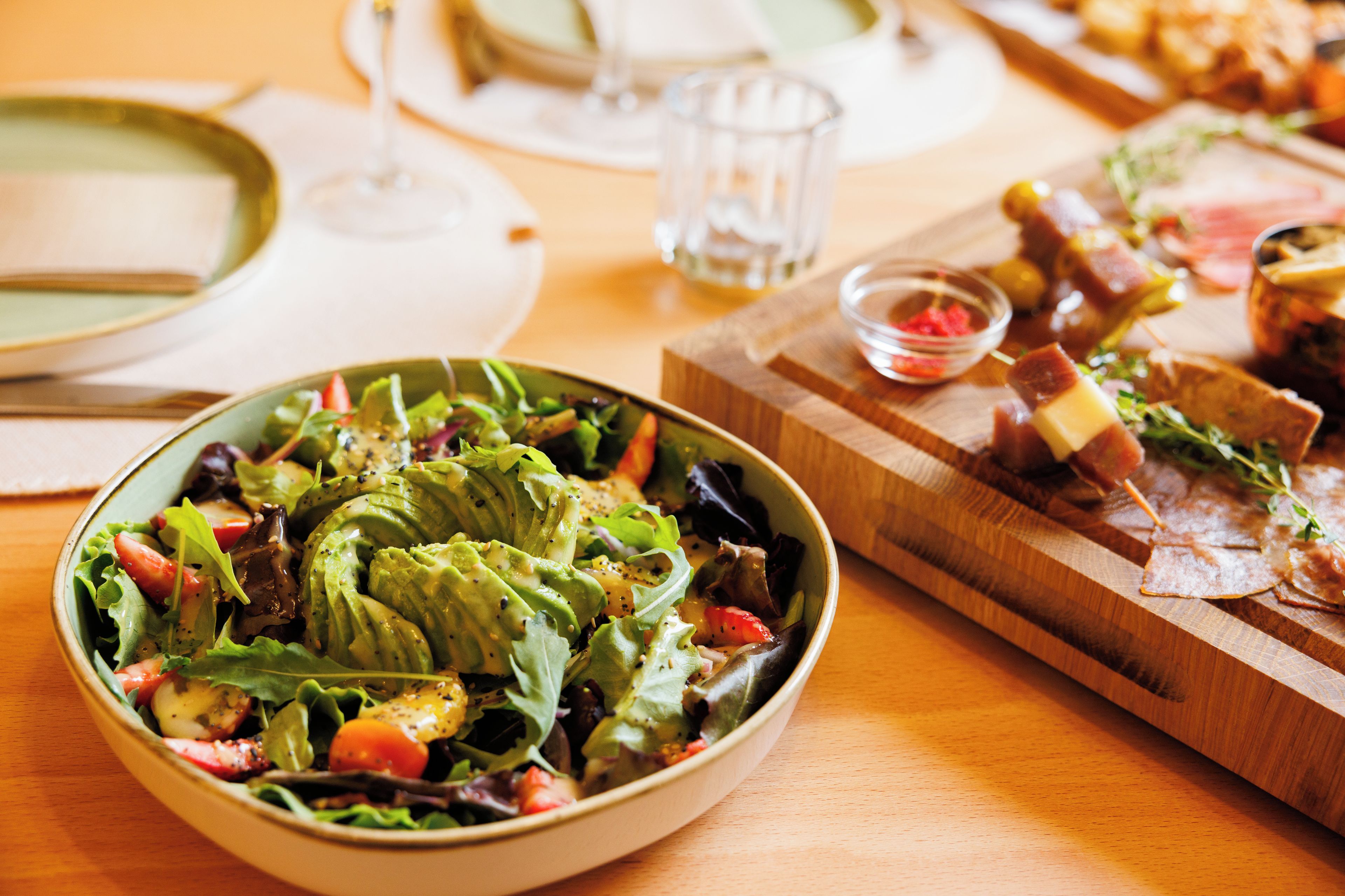 A dining table with a variety of dishes including a salad, a plate of meat, and a bowl of soup.