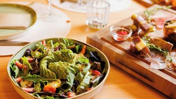 A dining table with a variety of dishes including a salad, a plate of meat, and a bowl of soup.