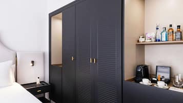 Una habitación de hotel con cama, mesita de noche, armario y estante con artículos de aseo.