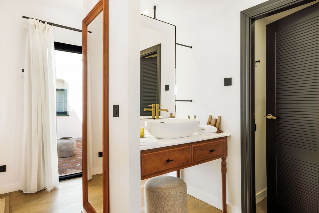 Un baño moderno con un espejo grande, un lavabo blanco y un mueble de tocador de madera.