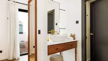 Un baño moderno con un espejo grande, un lavabo blanco y un mueble de tocador de madera.