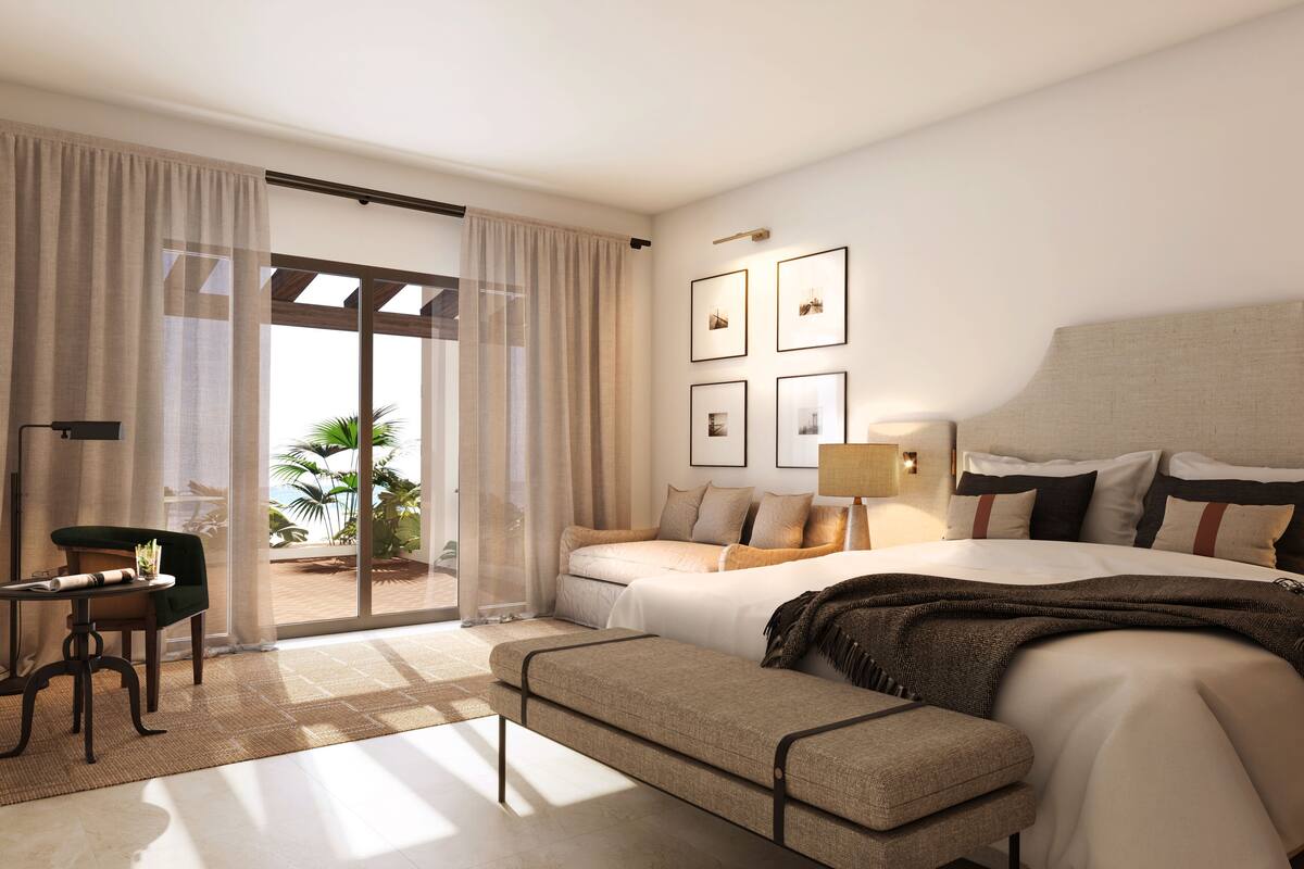 Habitación de hotel moderna con una cama grande, un escritorio y vistas a palmeras a través de la puerta de vidrio.