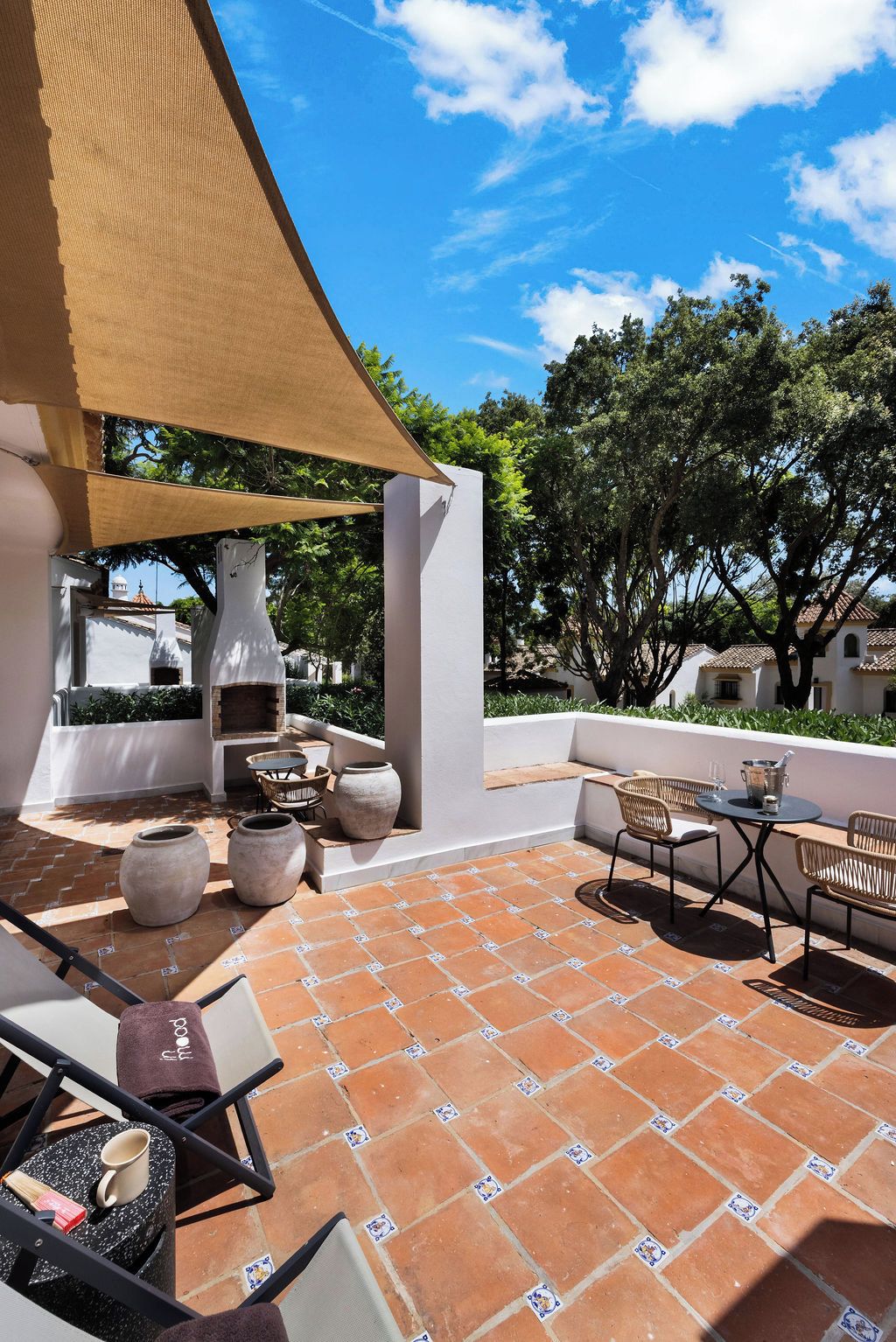 Un patio exterior con zona de barbacoa, mobiliario y vistas del paisaje circundante.