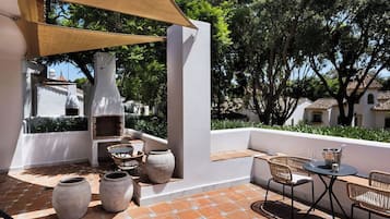 Un patio exterior con zona de barbacoa, mobiliario y vistas del paisaje circundante.