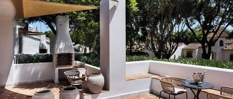 An outdoor patio with a barbecue area, seating, and a view of the surrounding landscape.