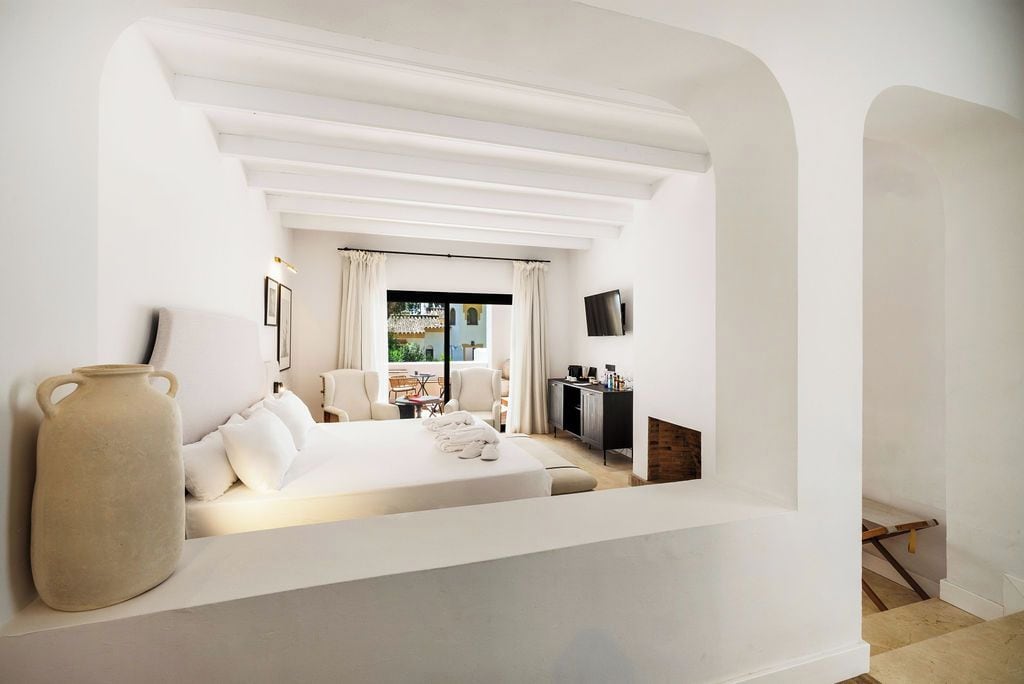 Een moderne hotelkamer met een bed, een bureau, een televisie en uitzicht op het groen.