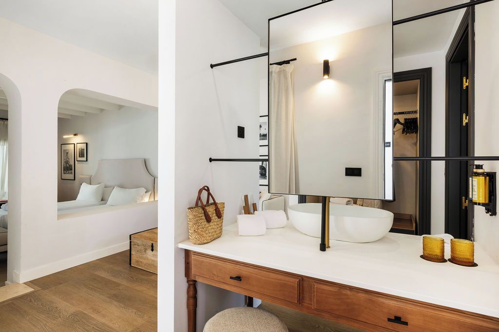 A modern bathroom with a large mirror, white sink, and wooden vanity.