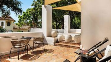 Un patio exterior con una mesa, sillas, un toldo y jarrones decorativos.