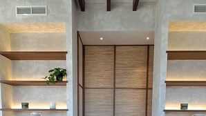 Un interior moderno con una mesa central, sillas y estanterías con iluminación.