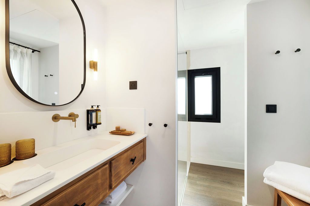 Een moderne badkamer met een grote spiegel, een wit wastafelmeubel en een douchecabine met glazen wanden.