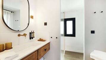 Een moderne badkamer met een grote spiegel, een wit wastafelmeubel en een douchecabine met glazen wanden.