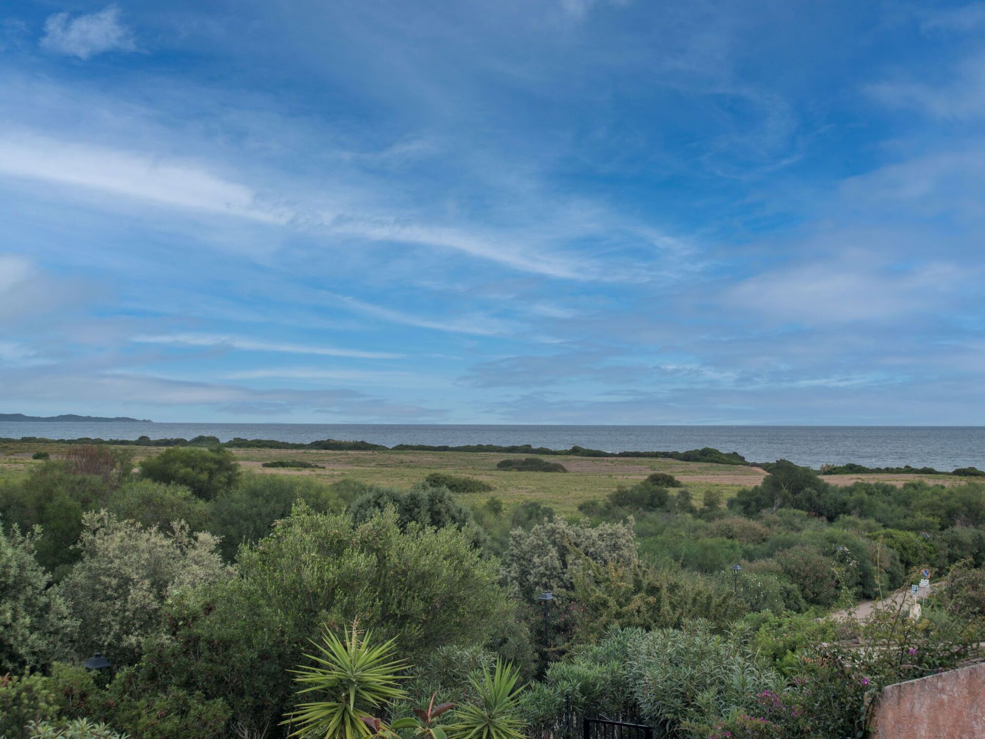 A coastal landscape with dense greenery and a clear view of the sea.