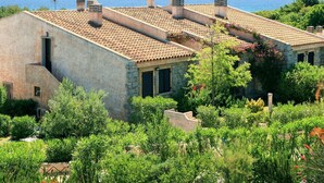 A Mediterranean-style building with a tiled roof, stone walls, and a view of the sea. - Nice apartment in villa for 4 guests with A/C, TV, terrace and pets allowed (Castiadas)