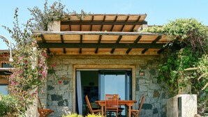 A stone building with a wooden pergola, a table and chairs outside, and a stone bench. - Nice apartment in villa for 4 guests with A/C, TV, terrace and pets allowed (Castiadas)