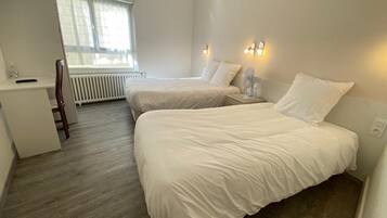 A hotel room with two beds, a desk, and a radiator.