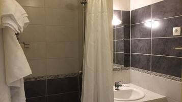 A bathroom with a shower, a sink, and a towel rack.
