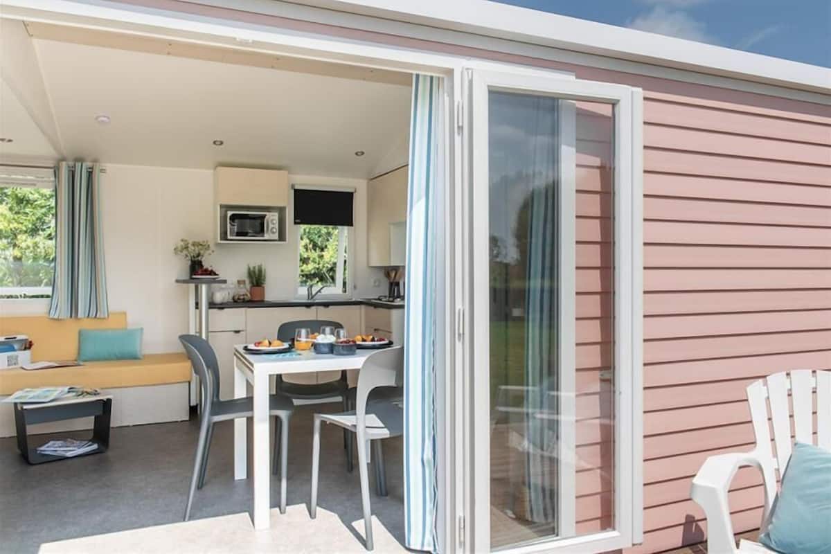 A modern, compact living space with a kitchenette, dining area, and a sliding glass door leading to an outdoor area.