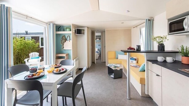 A modern, compact living space with a dining area, kitchenette, and a sofa.