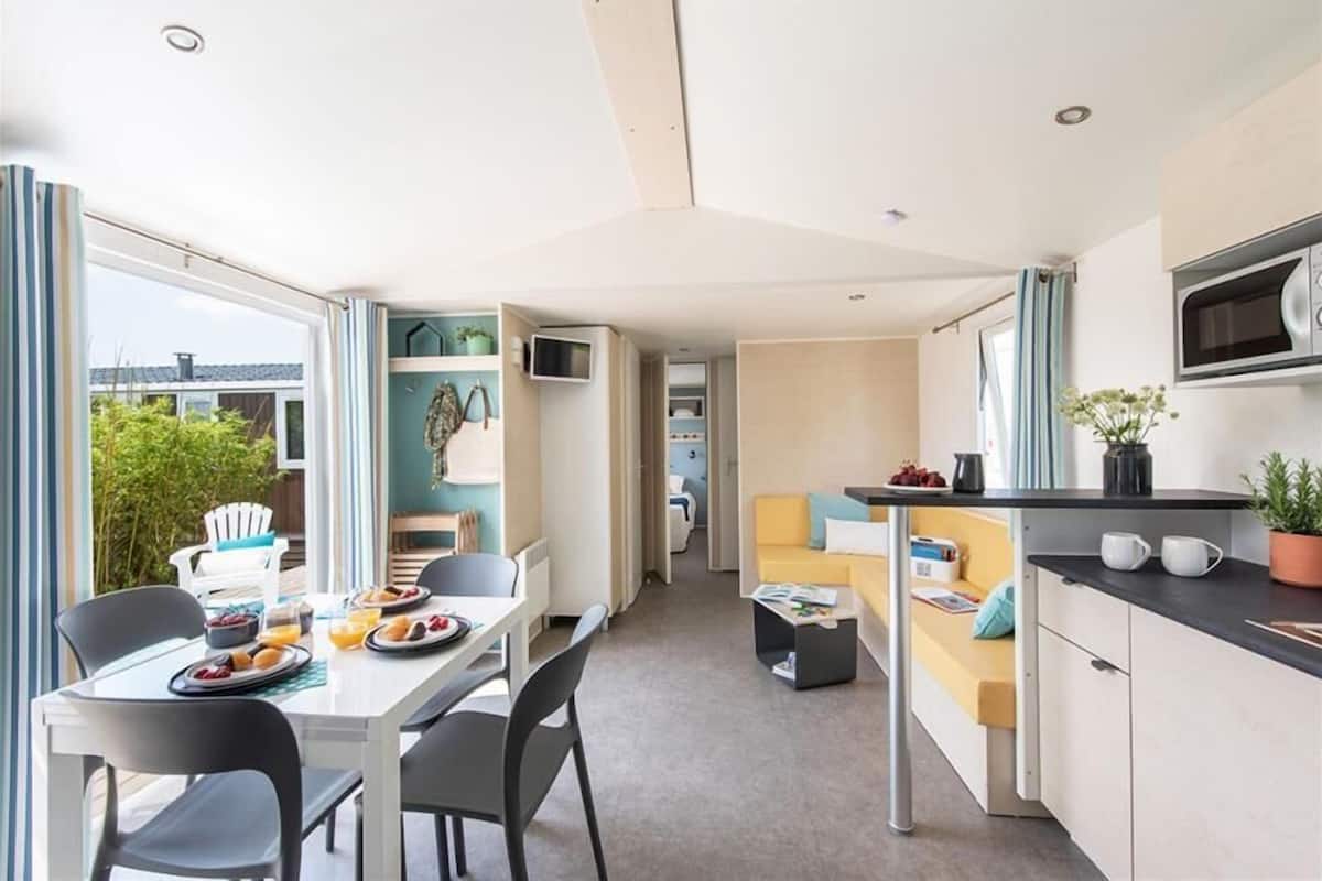 A modern, compact living space with a dining area, kitchenette, and a sofa.