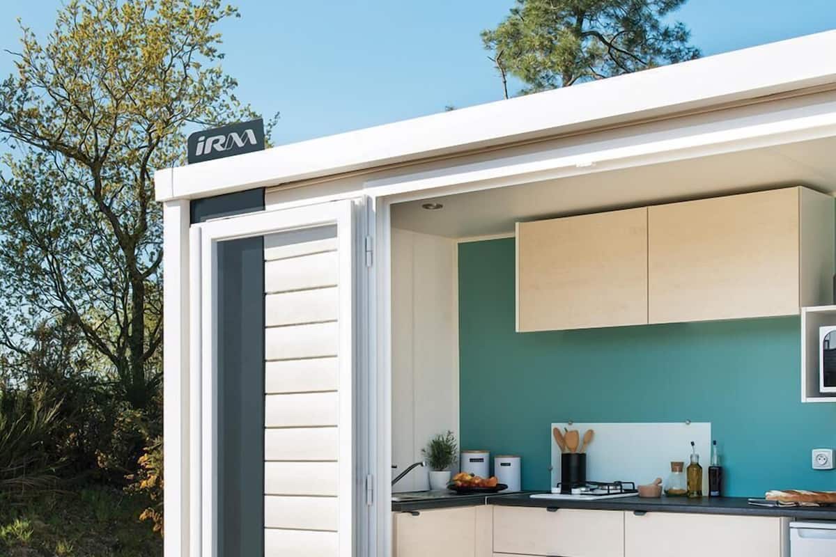 A compact, modern kitchen with a teal backsplash, white cabinets, and a small dining area with a table and chairs.