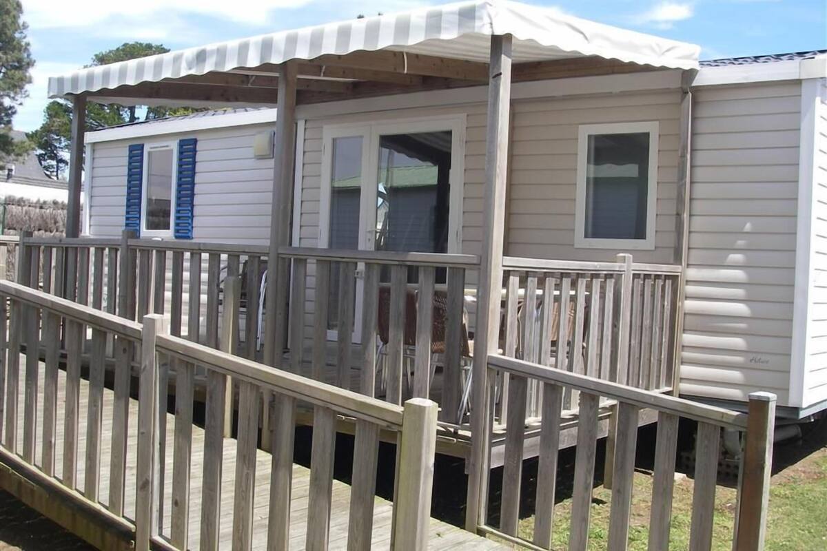 A mobile home with a covered porch and a wooden deck.
