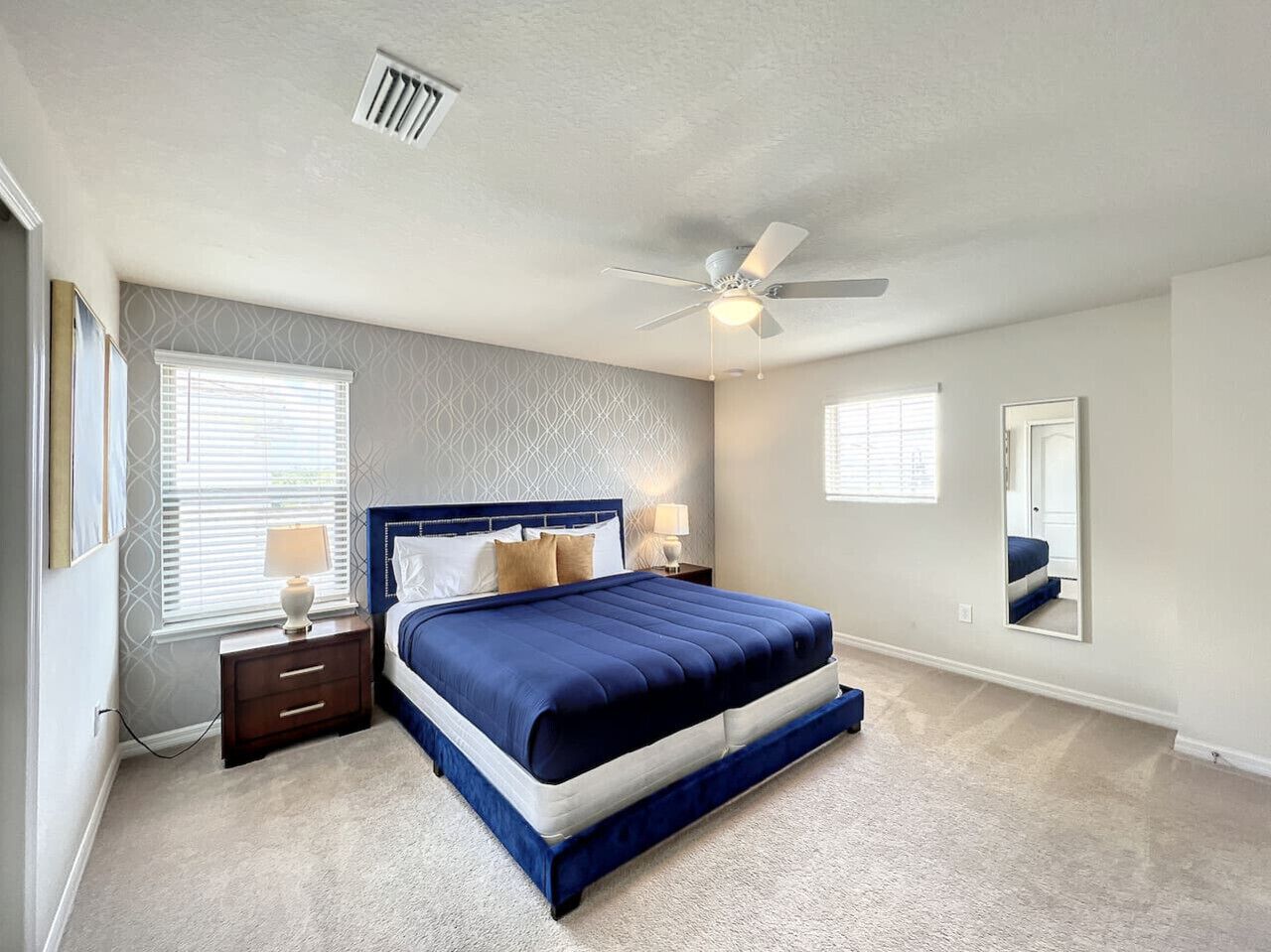 A bedroom with a large bed, a ceiling fan, and a window with blinds.