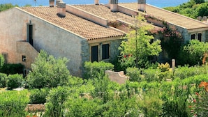 A Mediterranean-style building with a tiled roof, stone walls, and a view of the sea.