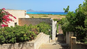 A stone staircase leading to a terrace overlooking a coastal landscape with a clear view of the sea and distant mountains.