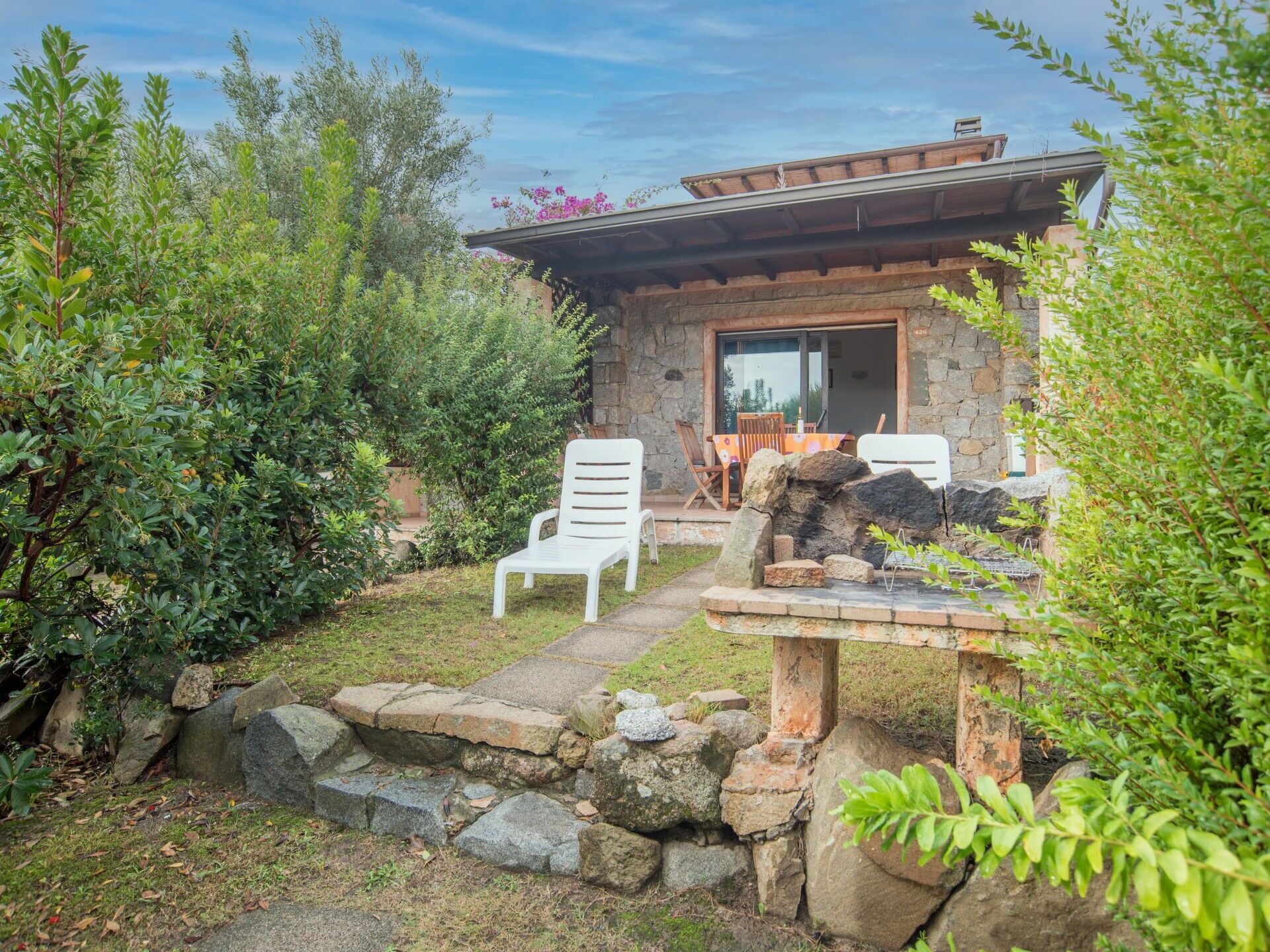 A stone house with a patio area, outdoor seating, and a small waterfall feature.