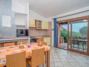 A compact kitchen with a dining area, a TV, and a sliding glass door leading to an outdoor patio. - Beautiful apartment in villa for 6 guests with A/C, TV, terrace and pets allowed (Sant'elmo)