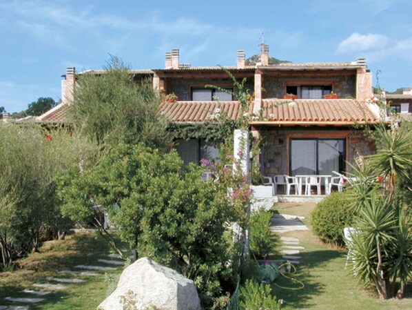 A two-story house with a tiled roof, surrounded by lush greenery and a stone pathway leading to the entrance. - Beautiful apartment in villa for 6 guests with A/C, TV, terrace and pets allowed (Sant'elmo)
