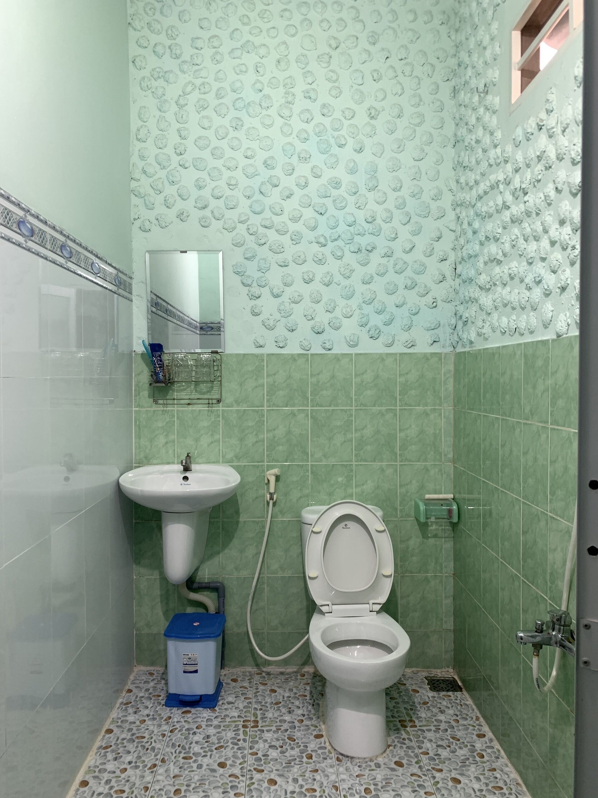 Et badeværelse med håndvask, toilet og spejl.